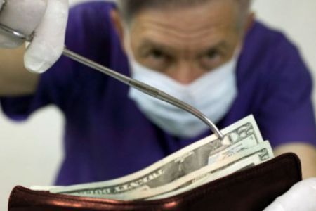 A Dentist Is Holding a Syringe Over a Wallet Full of Money — Alchemy Wellness Centre In Bangalow, NSW