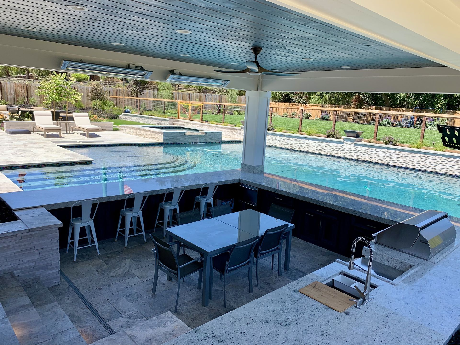 Backyard with a pool, concrete countertops being constructed, a gas heater, and wooden fence.