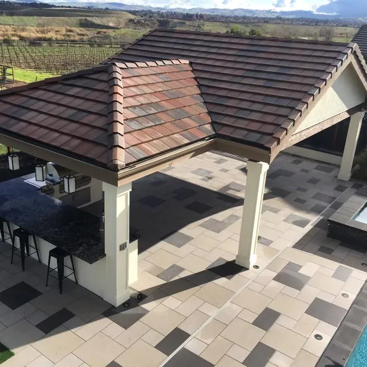 Patio with tiled roof, outdoor kitchen, and stone paving. View of vineyards in the background.