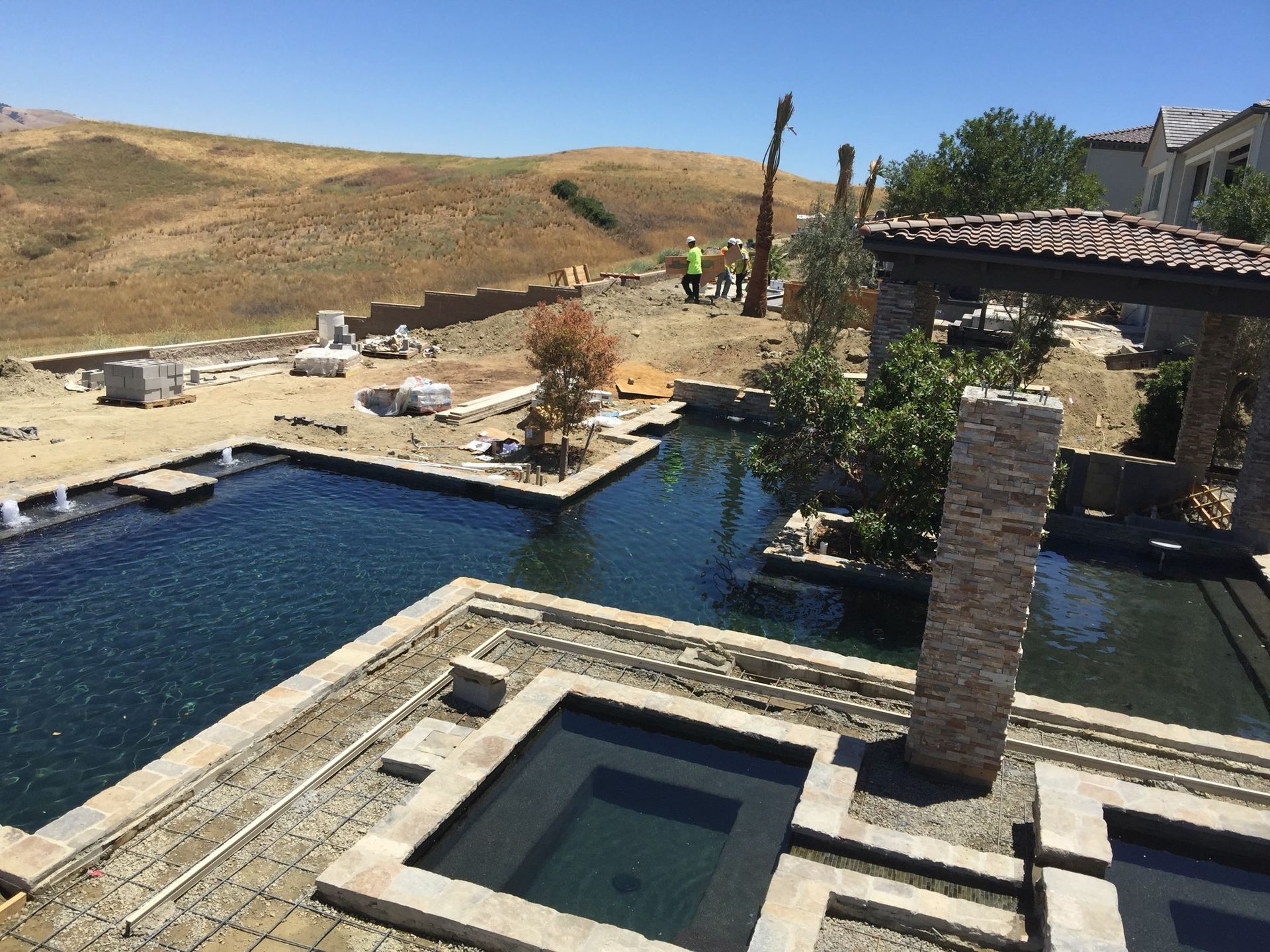 Construction of a multi-pool backyard with a mountainous backdrop.