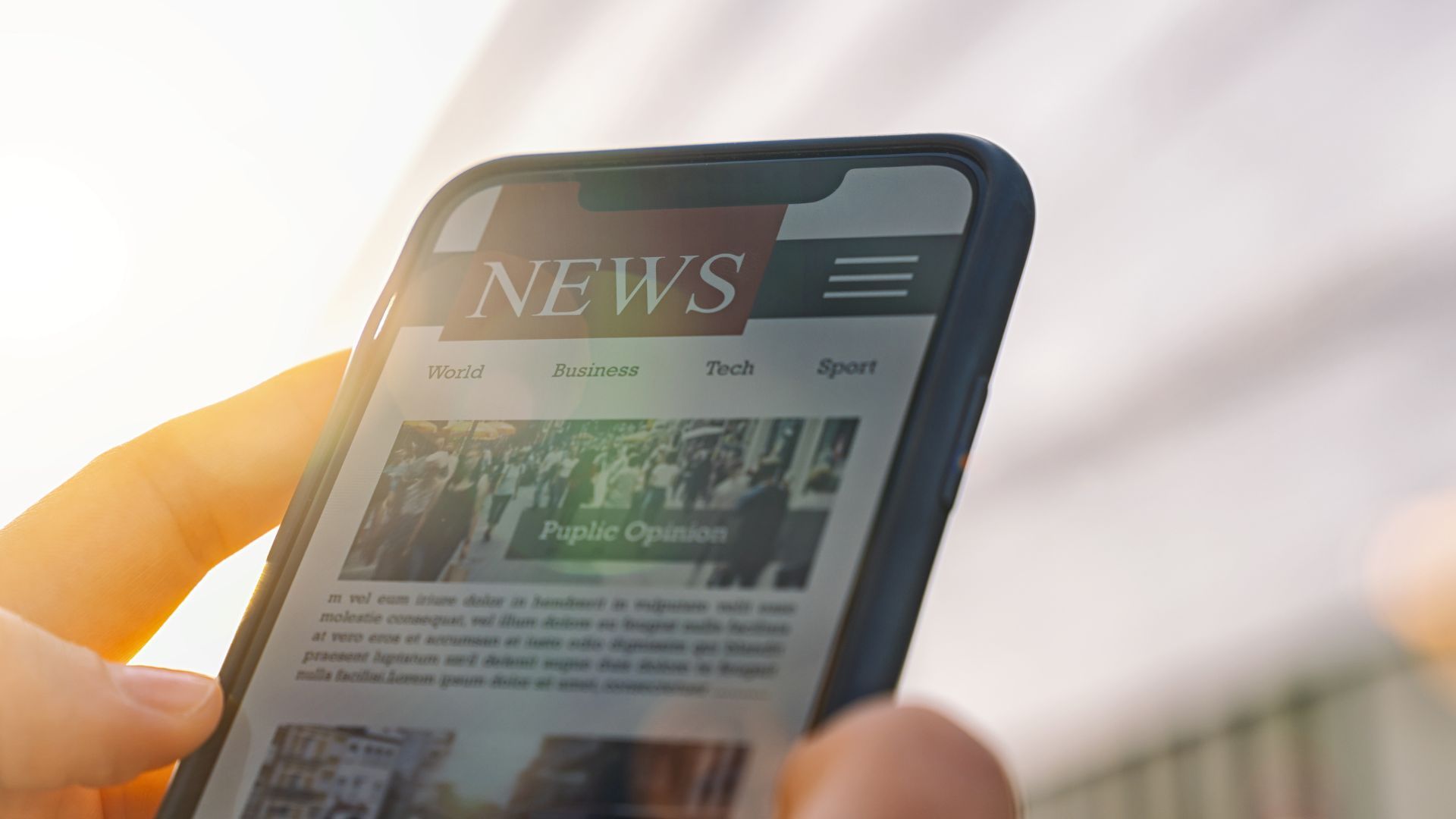 a person is holding a cell phone with a news website on it .