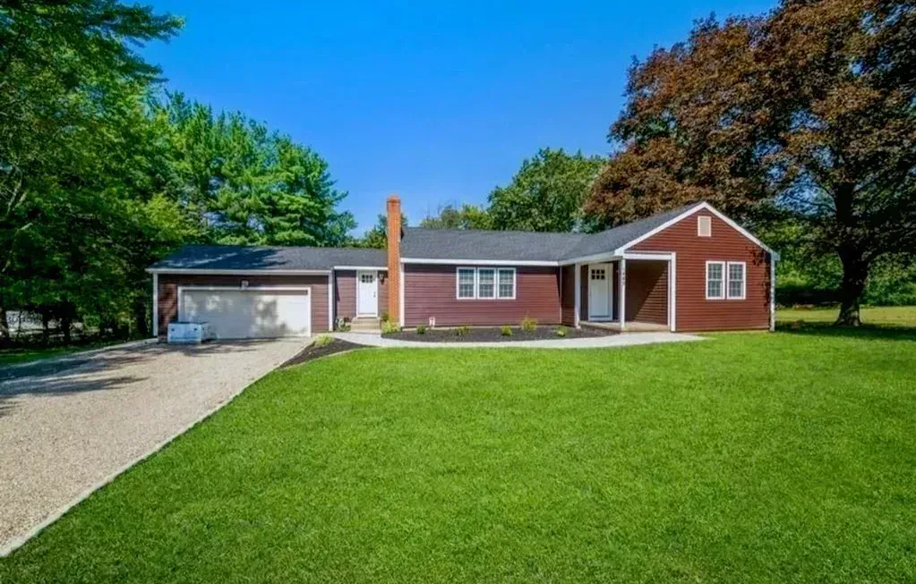 A red house with a large lawn in front of it.