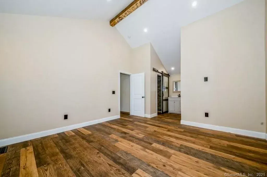 A large empty room with wooden floors and beige walls.