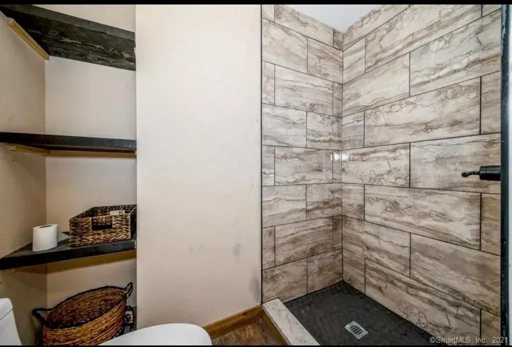 A bathroom with a toilet and a walk in shower.