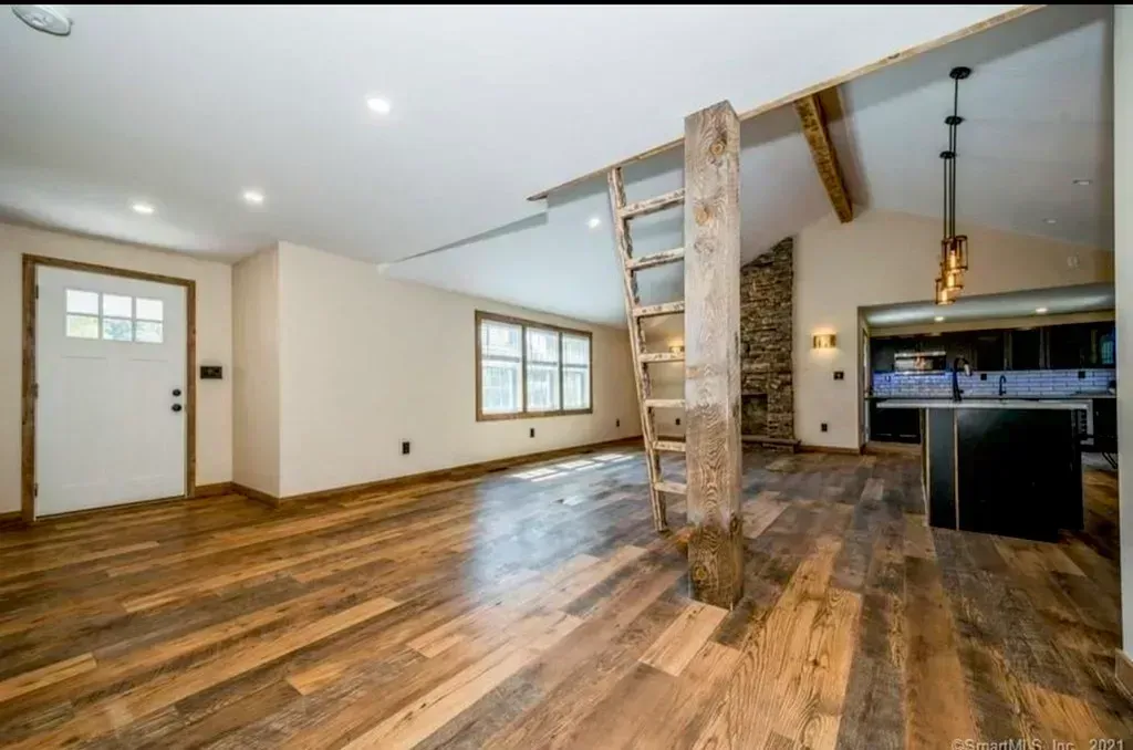 An empty room with wooden floors and a ladder