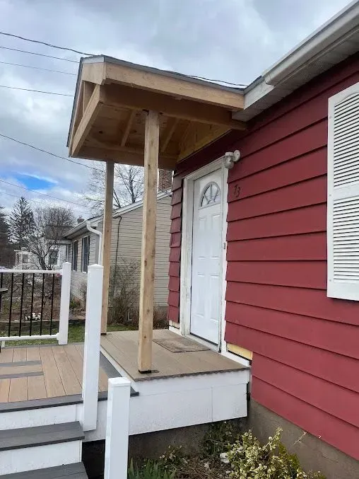 A red house with a porch and stairs leading to it.