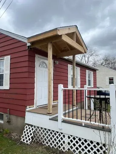 A red house with a porch and a white railing.