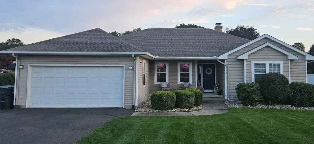 A house with a large garage door and a lush green lawn.