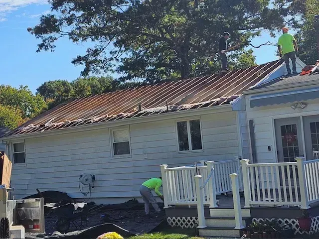 Two men are working on the roof of a house.