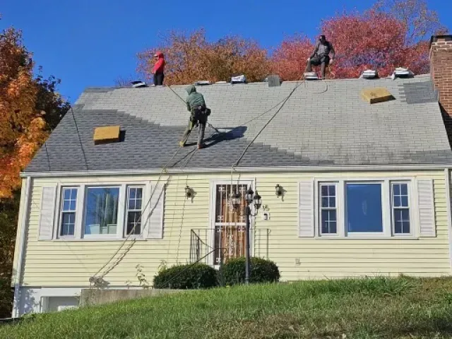 Two men are working on the roof of a house.