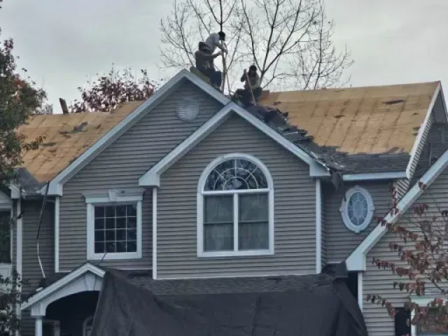 Two men are working on the roof of a house