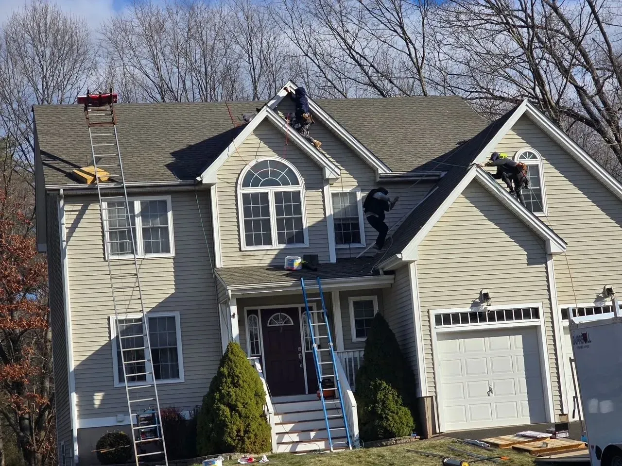 Two men are working on the roof of a house.