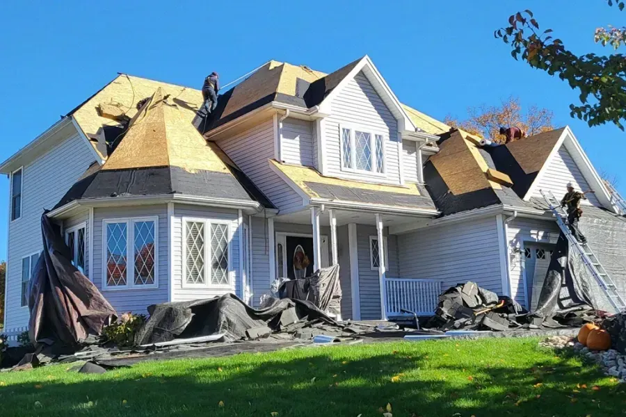 A large white house with a roof being installed