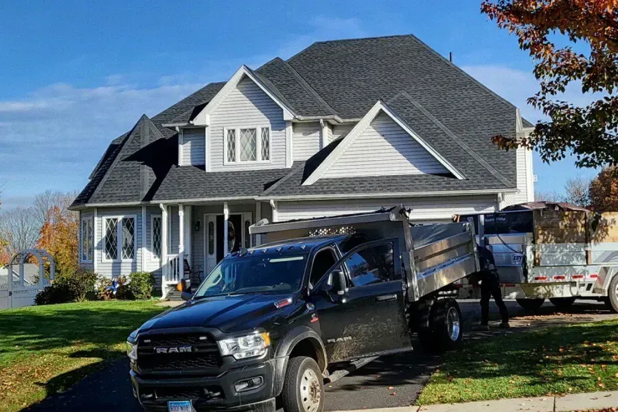 A black truck is parked in front of a large house.