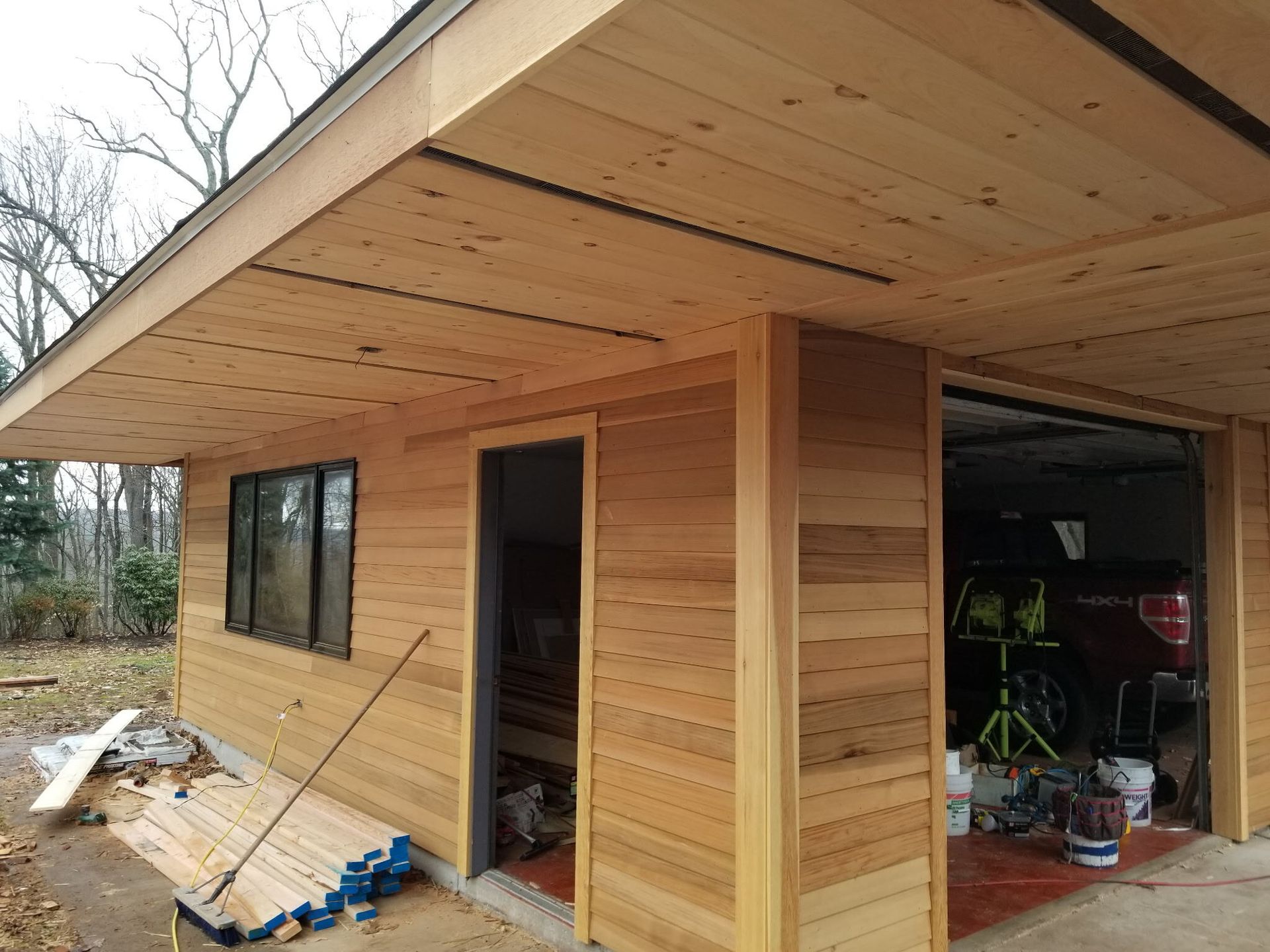 A wooden garage with a red truck parked in it