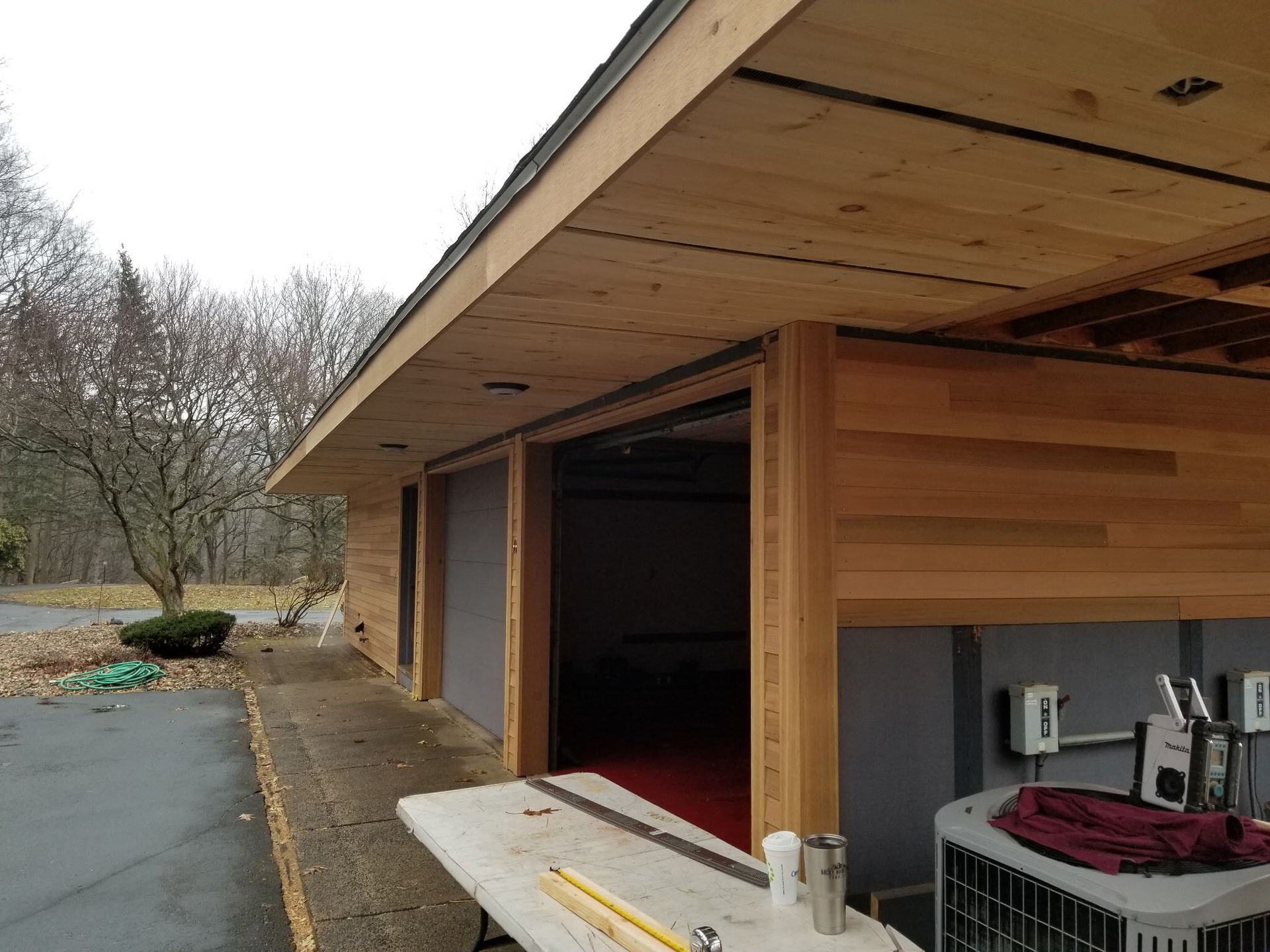 A white table in front of a building with a roof that has wood paneling on it