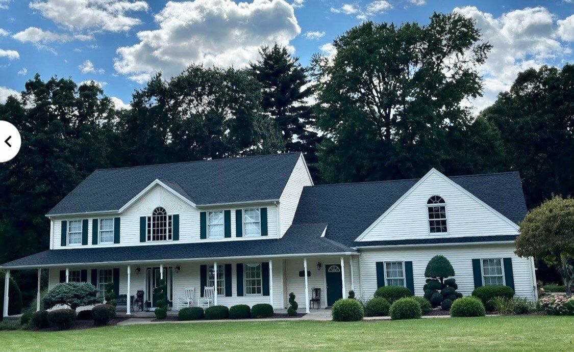 A large white house with a blue roof and green shutters
