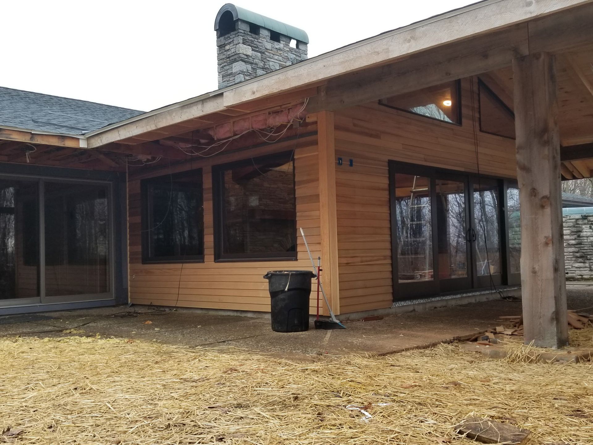 A large wooden house with a black trash can in front of it