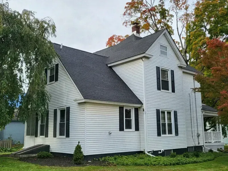 A white house with black shutters and a black roof