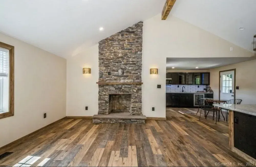 A living room with a stone fireplace and wooden floors.
