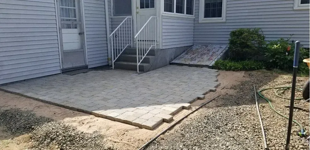 A patio is being built in front of a house with stairs.