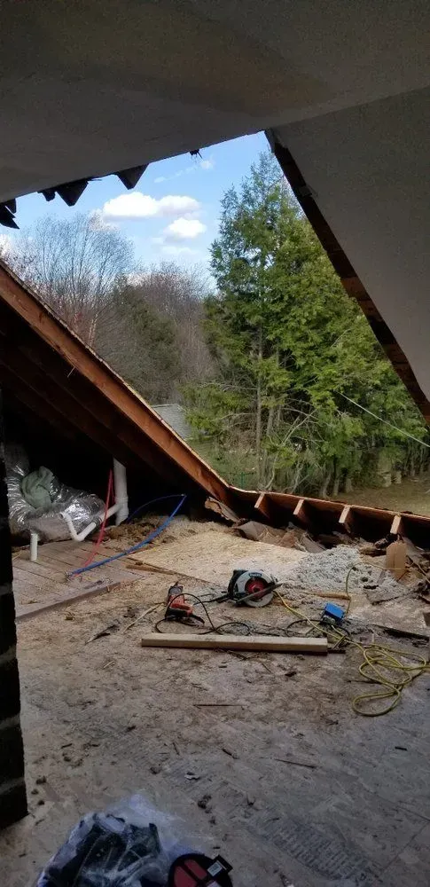 A room with a roof that is being remodeled and a view of a forest.