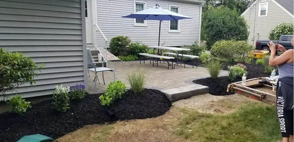 A man is standing in front of a house taking a picture of a patio.