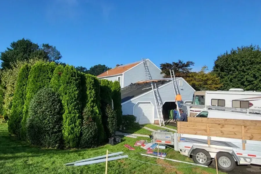A house is being painted and a trailer is parked in front of it.