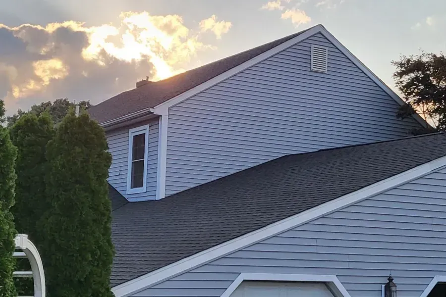 The sun is shining through the clouds on the roof of a house.