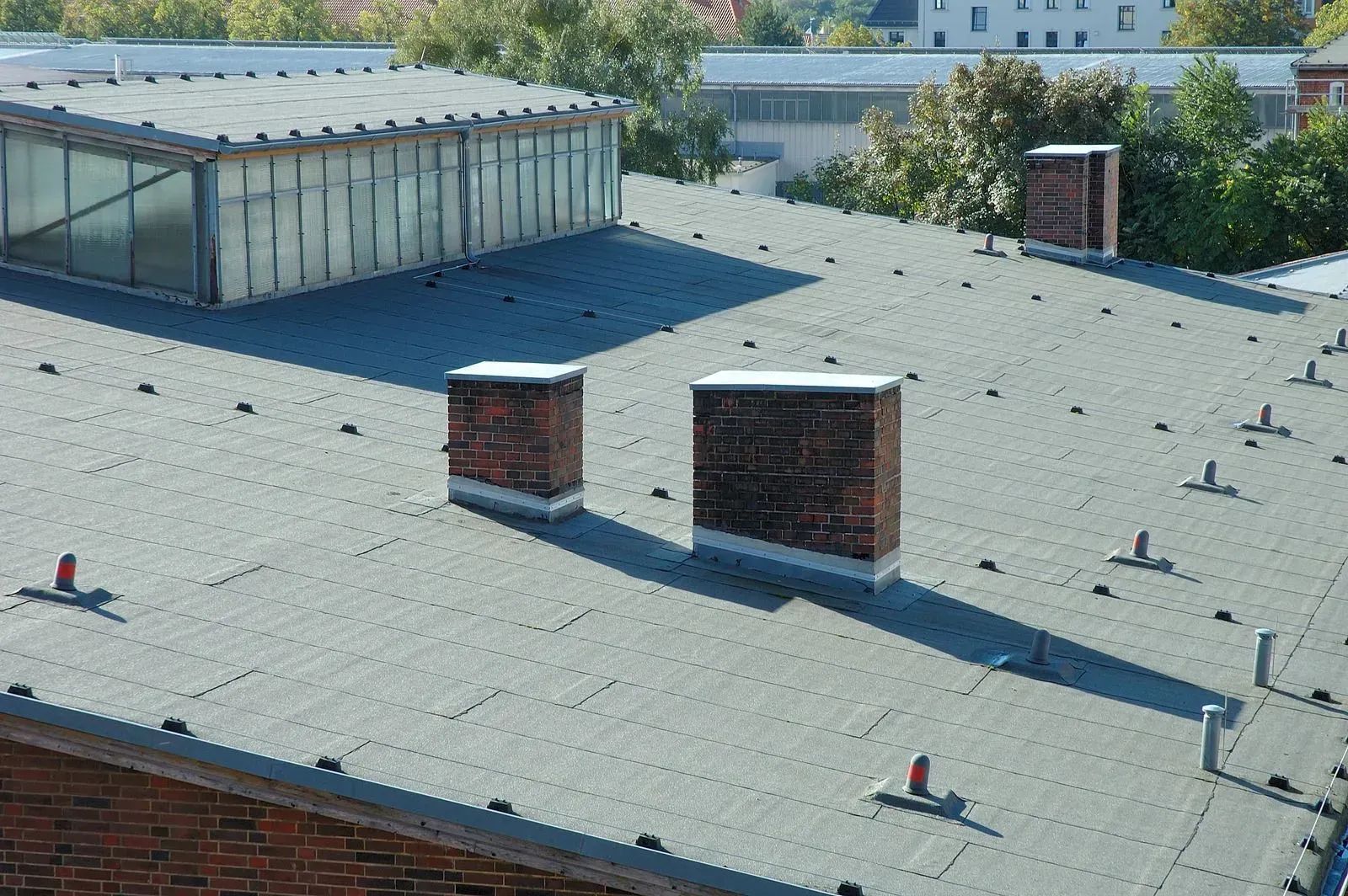 Flat roof with three brick chimneys and a glass skylight.