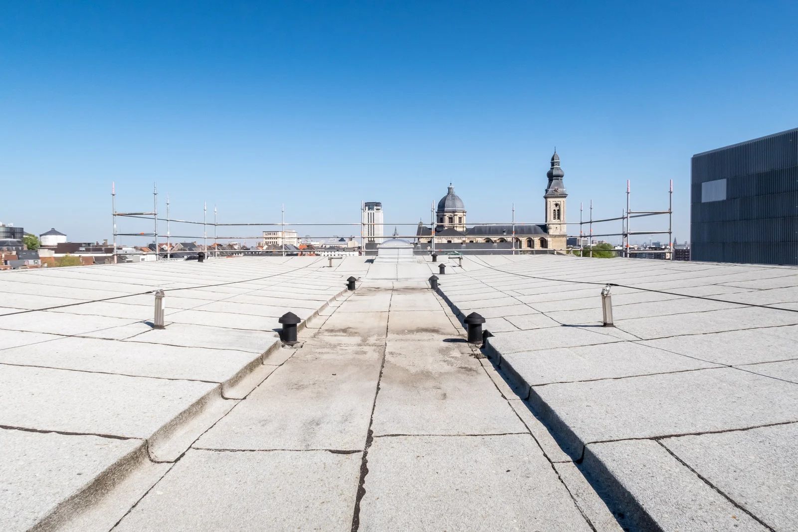 Rooftop view with buildings, clear sky, and church with dome and spire in the background.