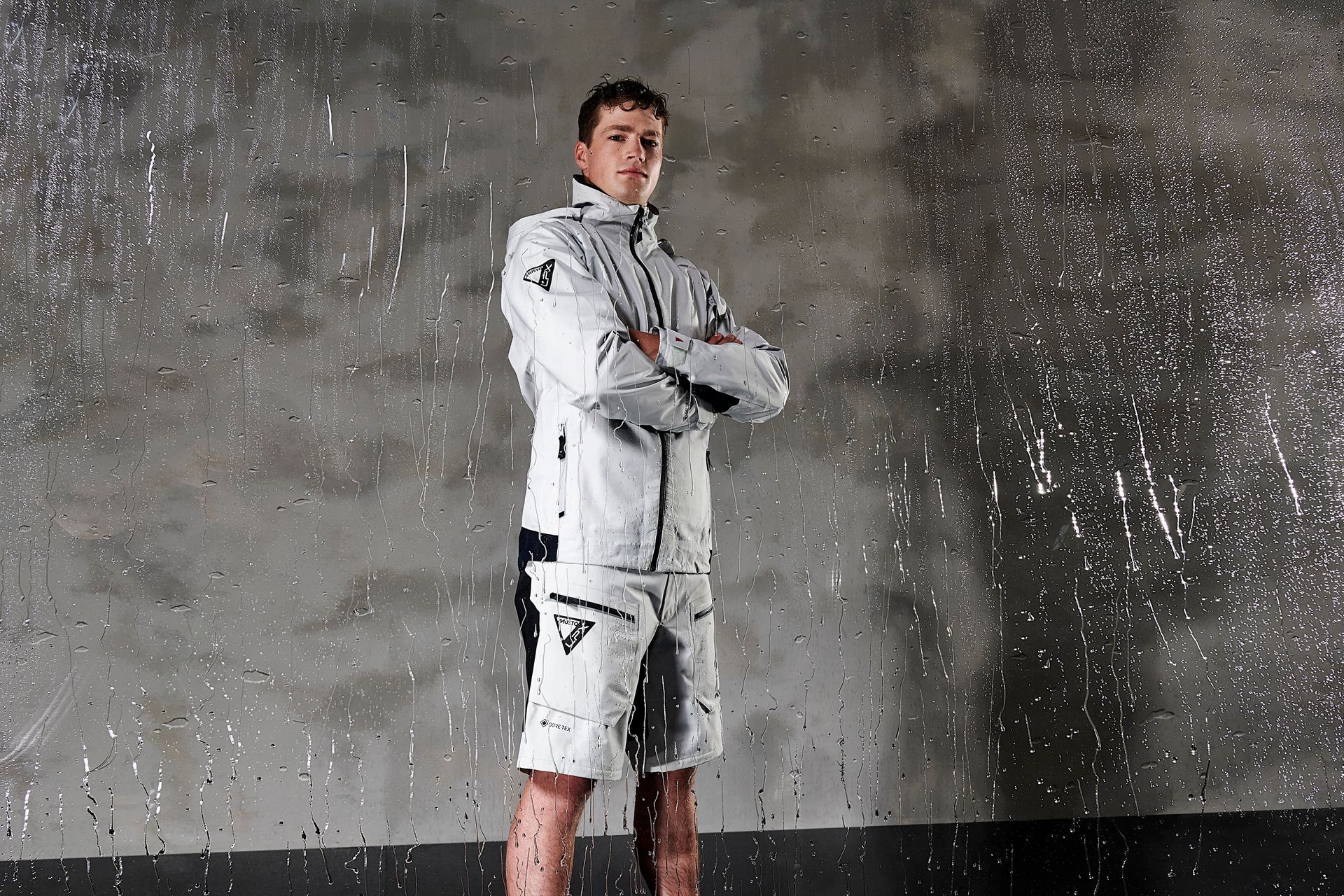 a man standing in the rain with his arms crossed