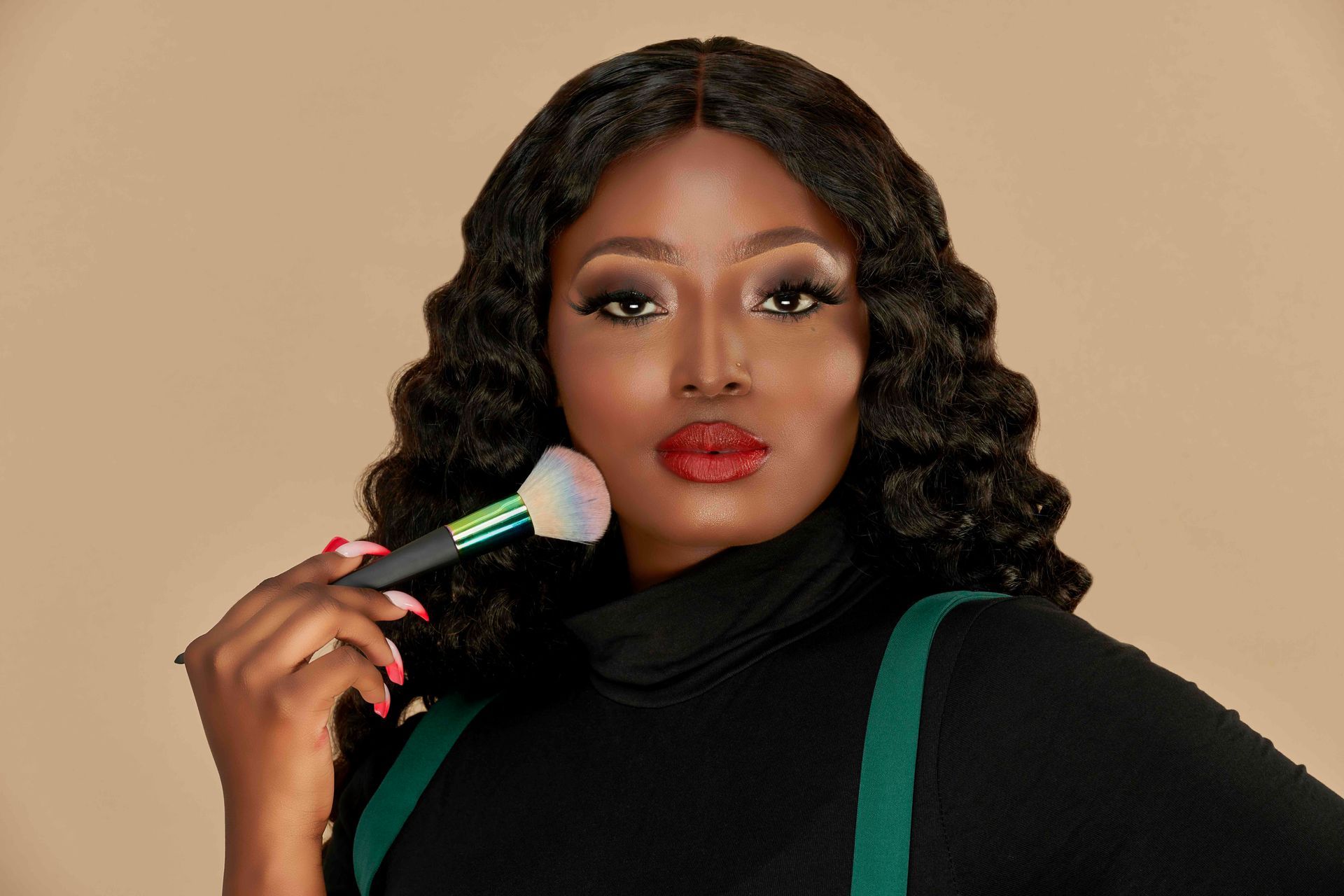 A woman is holding a makeup brush in front of her face.