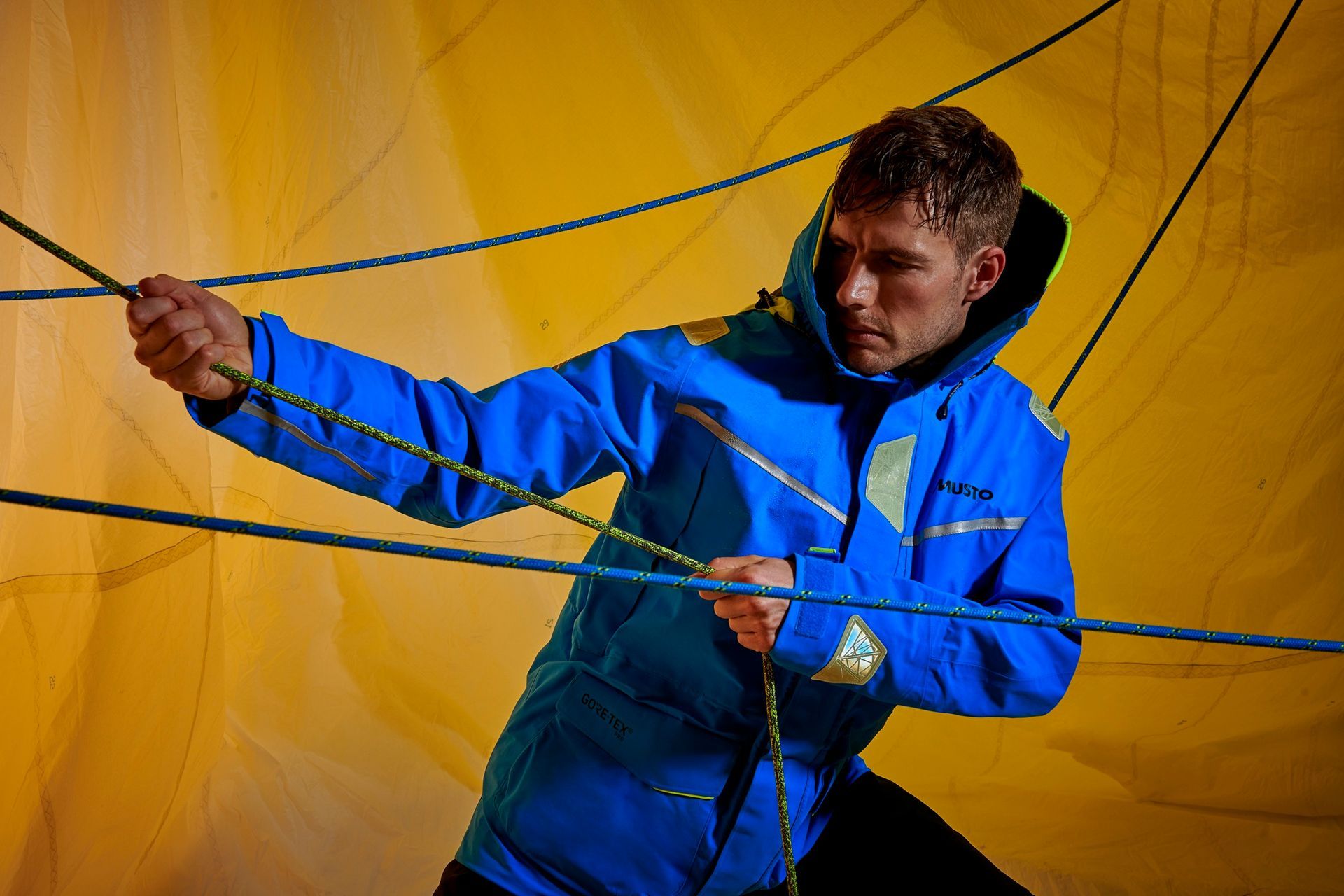a man in a blue jacket is playing with ropes .