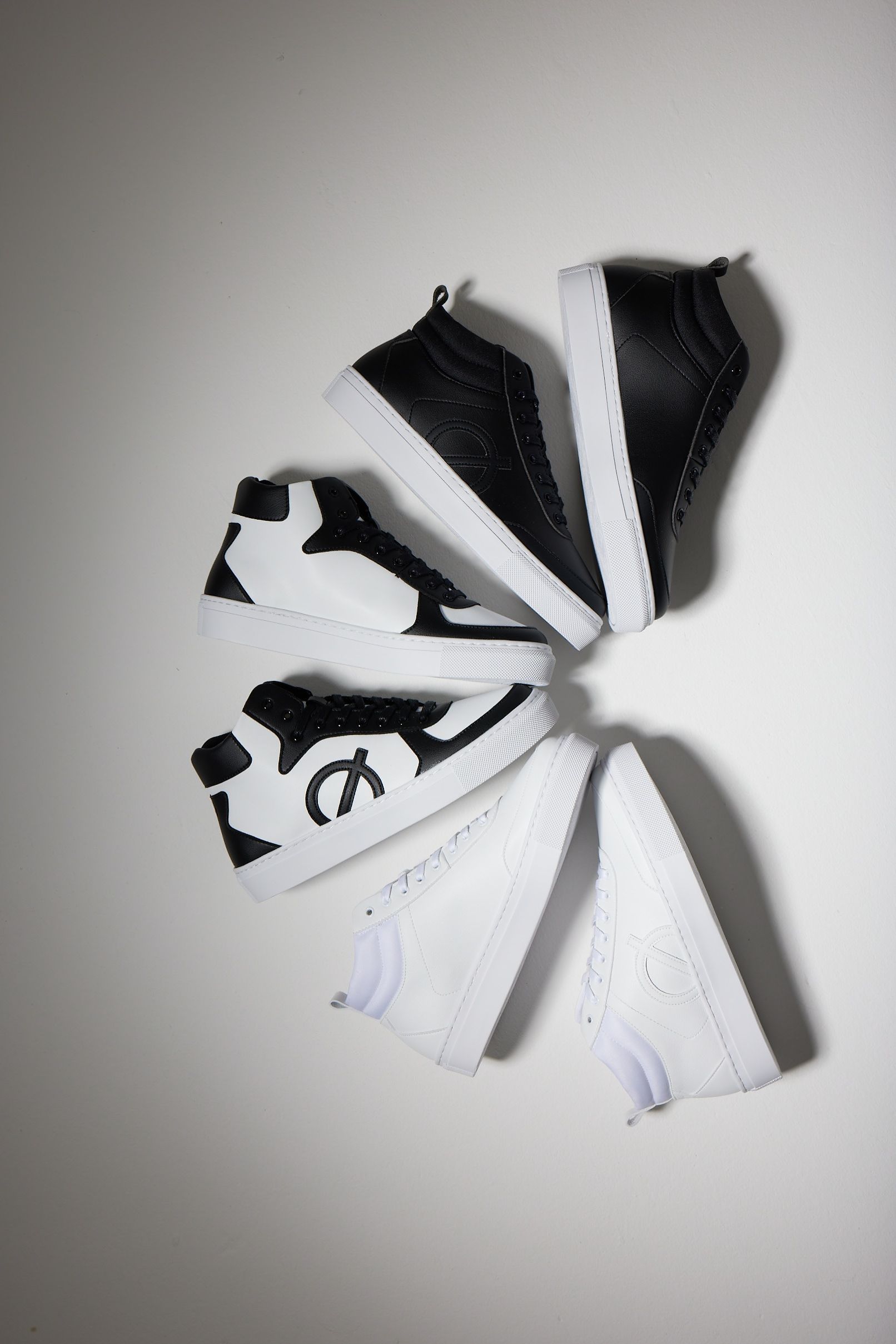 a group of black and white sneakers are stacked on top of each other on a white surface .