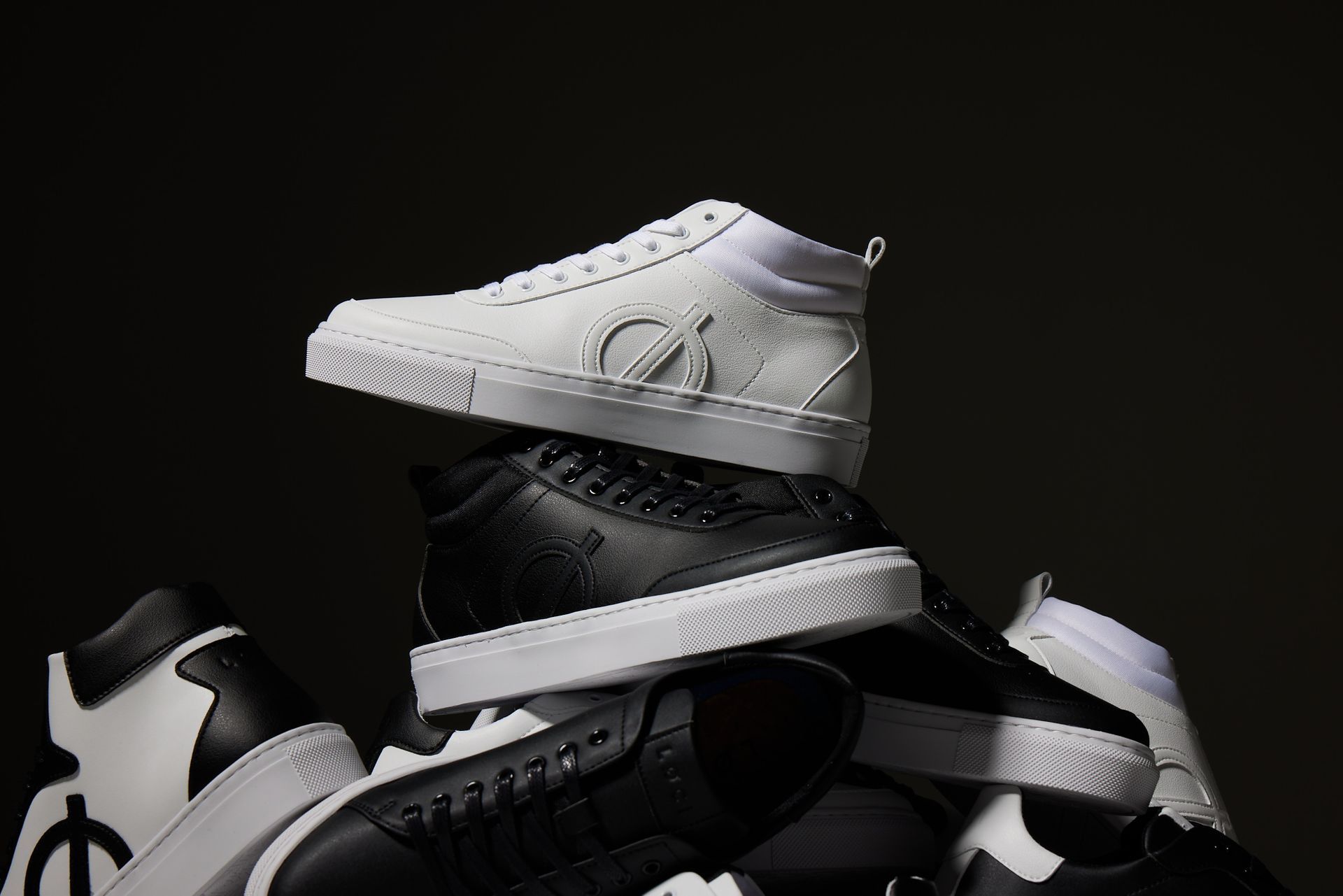 a pile of black and white sneakers stacked on top of each other .