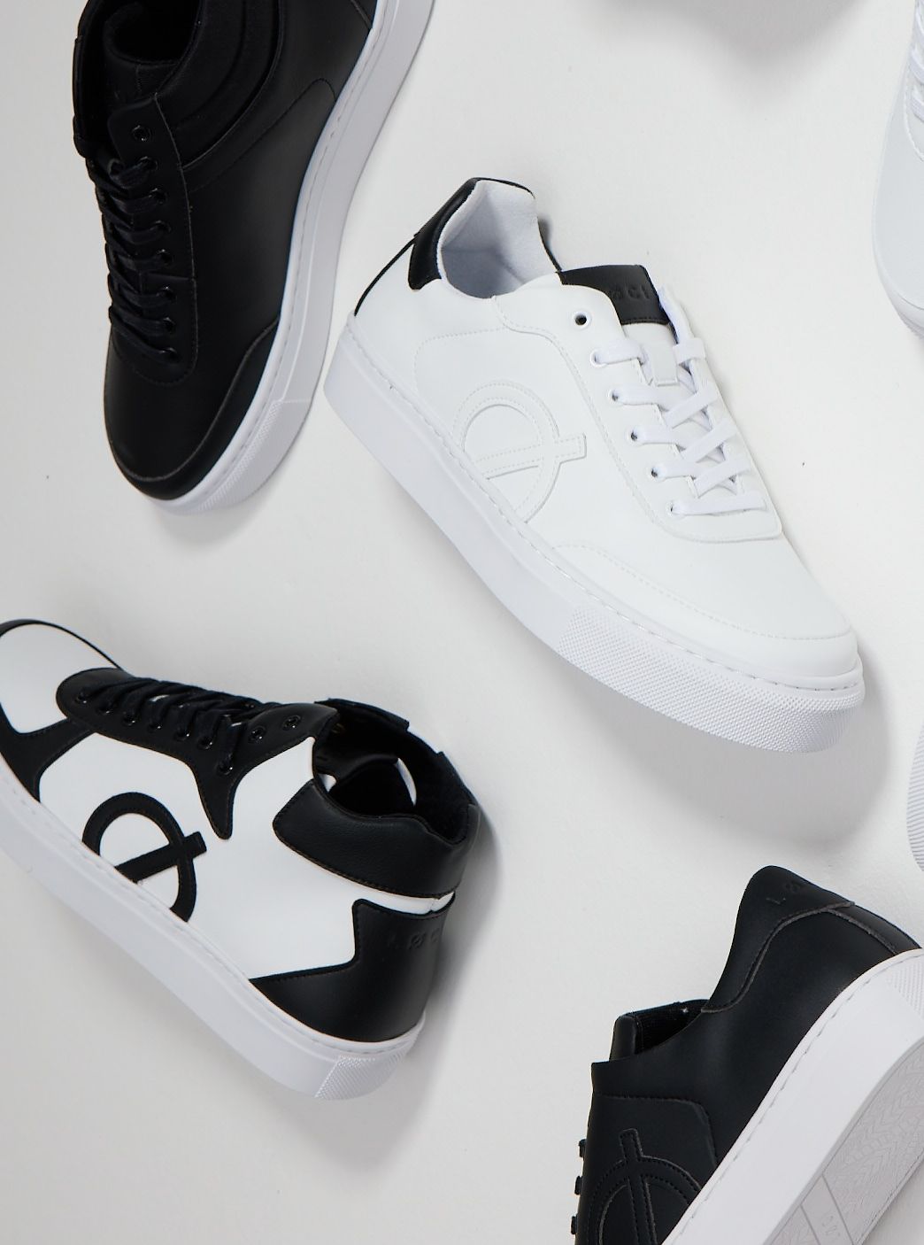 a group of black and white sneakers are laying on a white surface