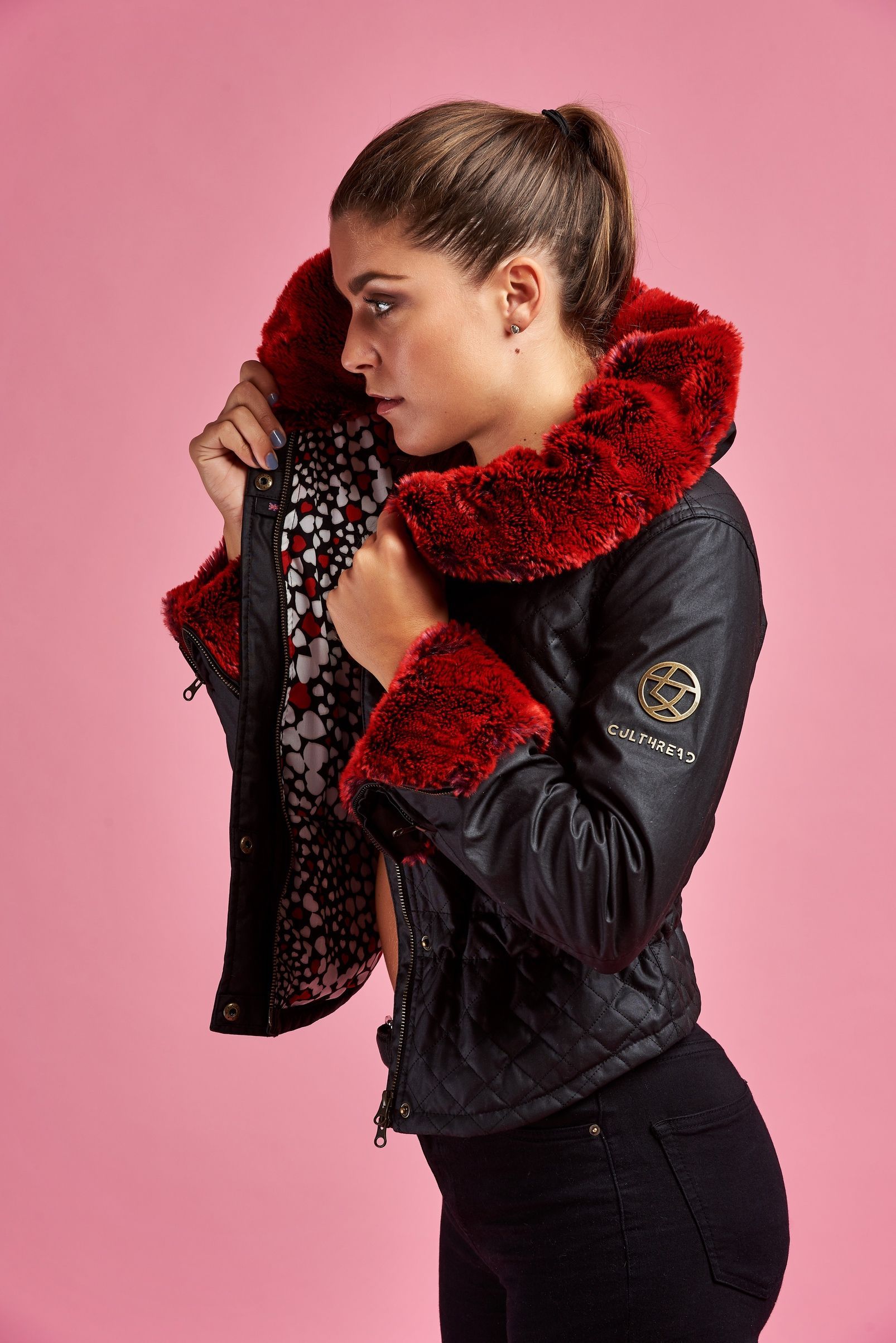 a woman is wearing a black leather jacket with a red fur collar .