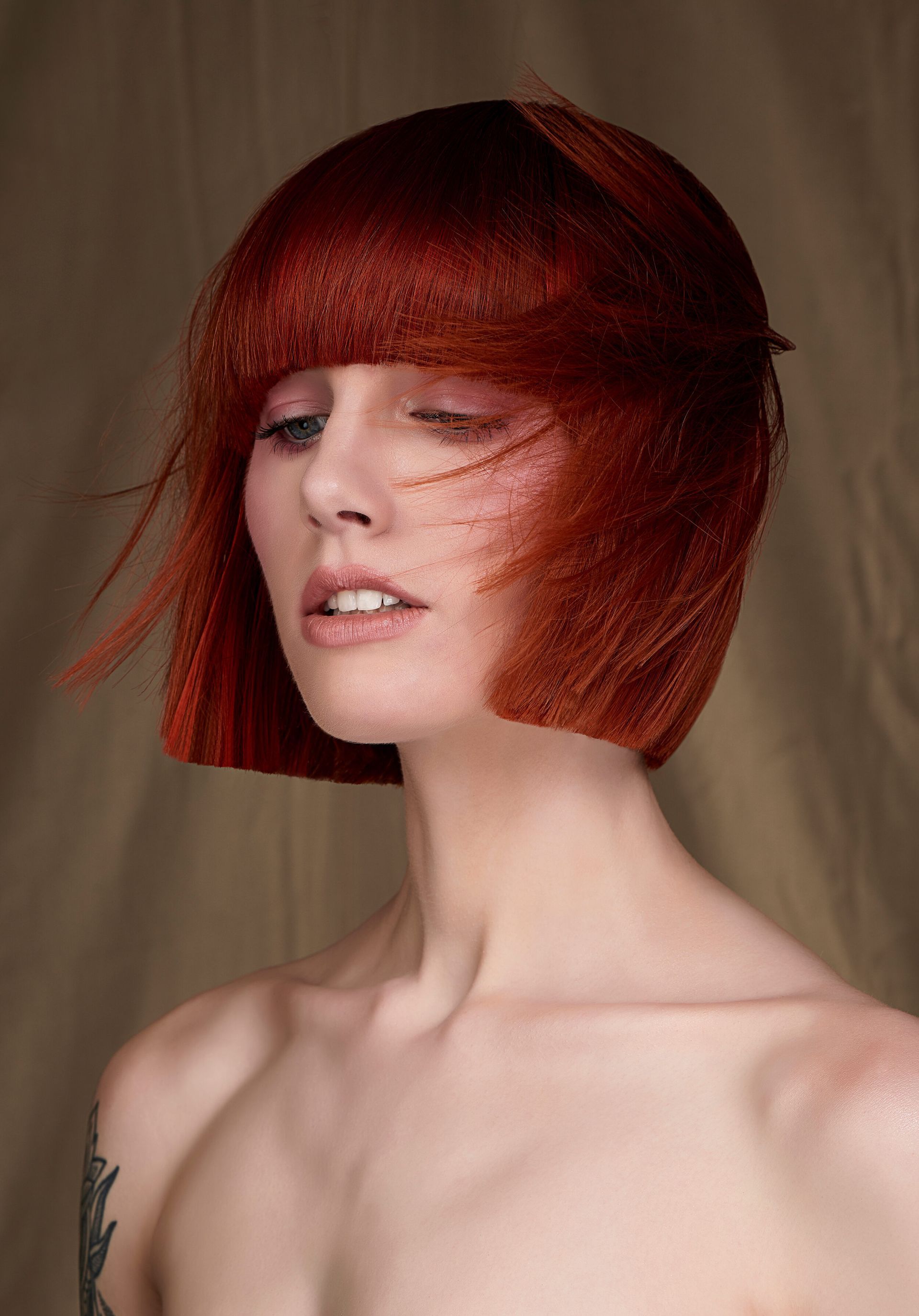 A woman with red hair and a tattoo on her arm.