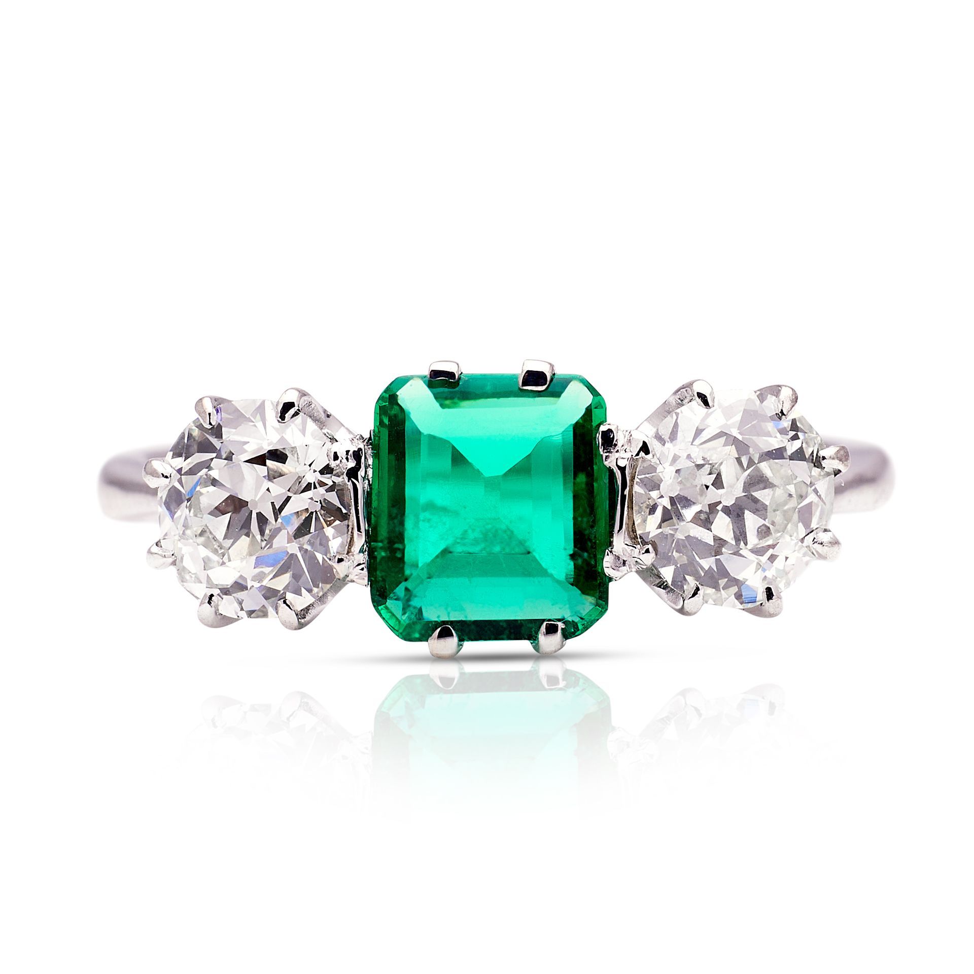 a ring with an emerald and two diamonds on a white background .