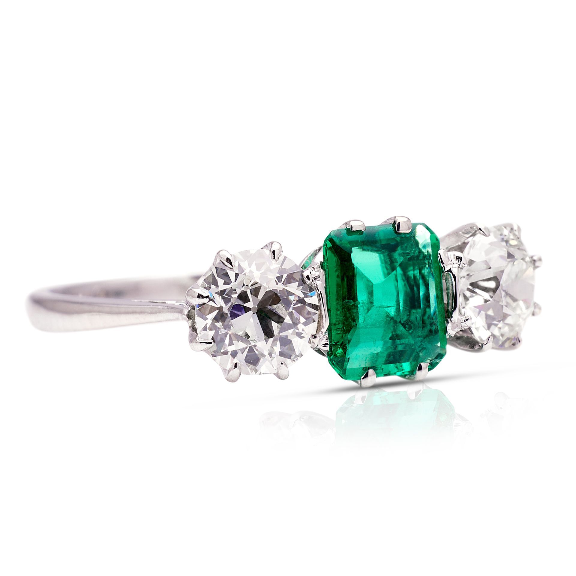 a ring with an emerald and two diamonds on a white background .
