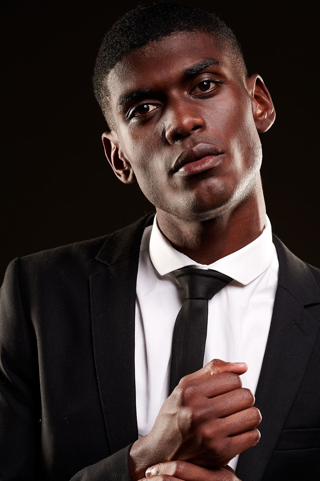 A man in a suit and tie is adjusting his collar.