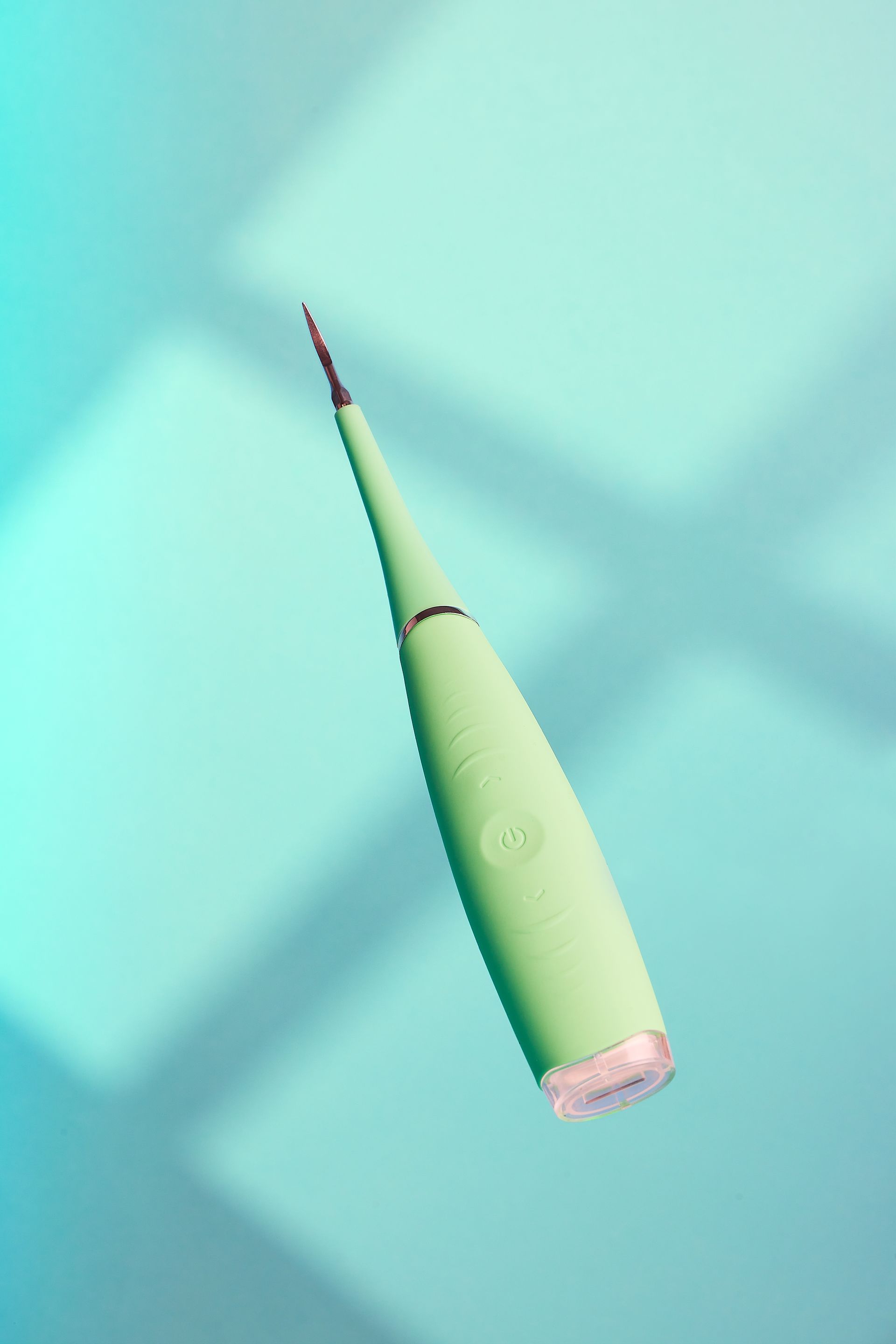 A green toothbrush is floating in the air on a blue surface.