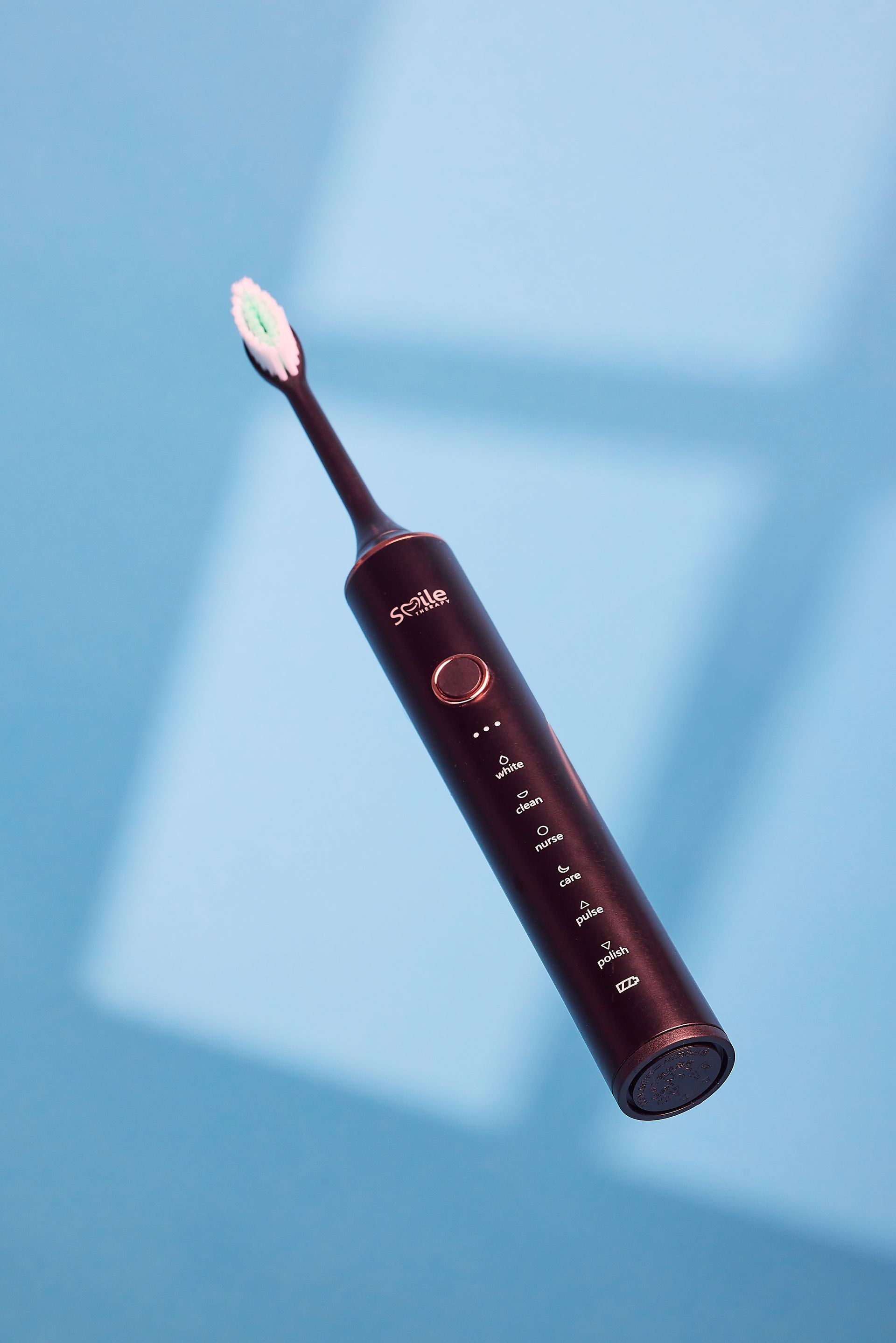 An electric toothbrush is floating in the air on a blue surface.