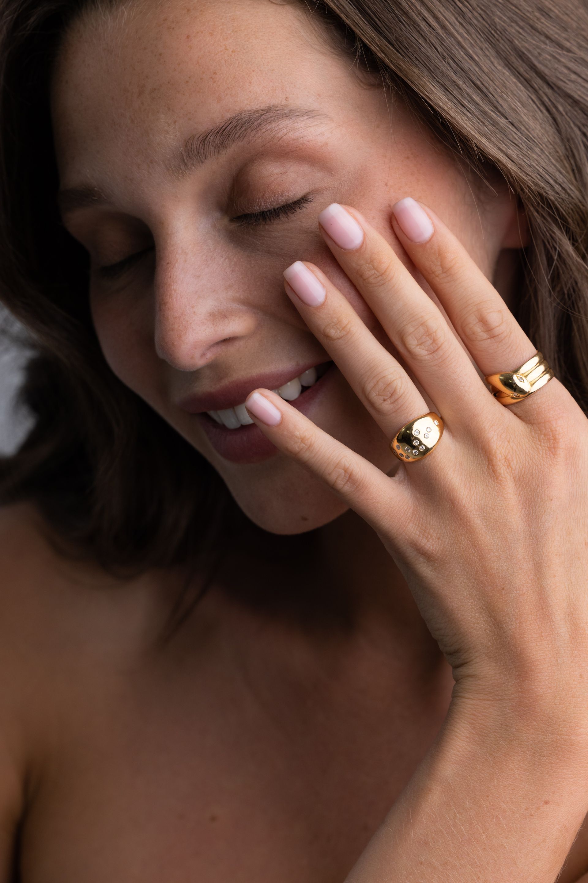 a woman is wearing two gold rings on her fingers .