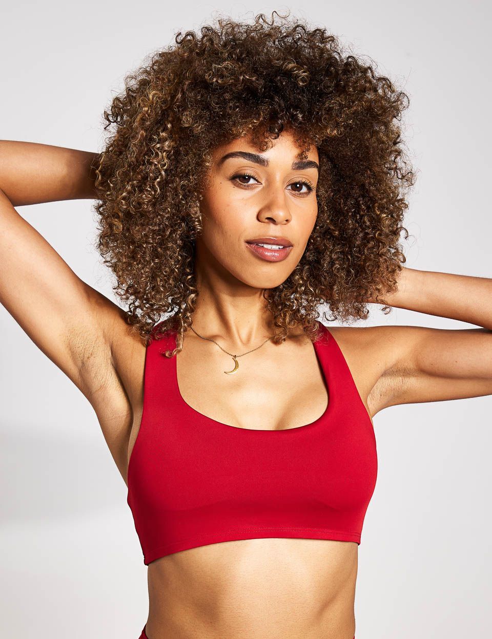a woman with curly hair is wearing a red sports bra .