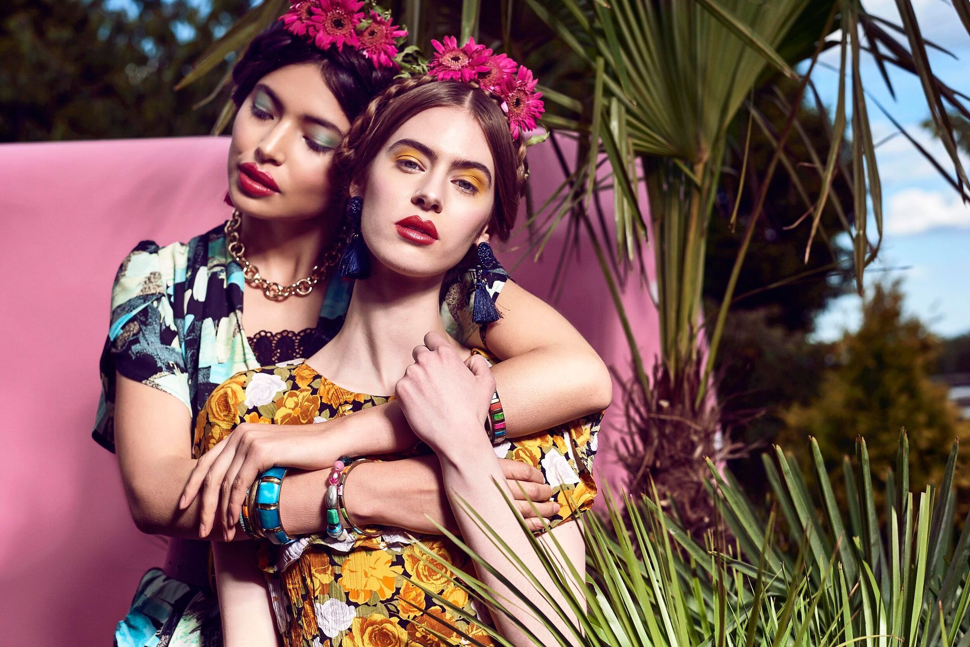Two women are posing for a picture with flowers in their hair.