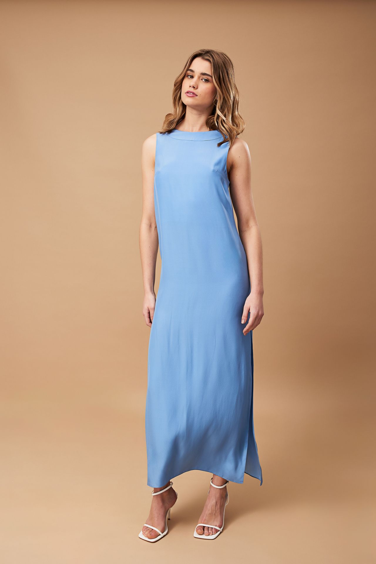 A woman is wearing a light blue dress and white heels.