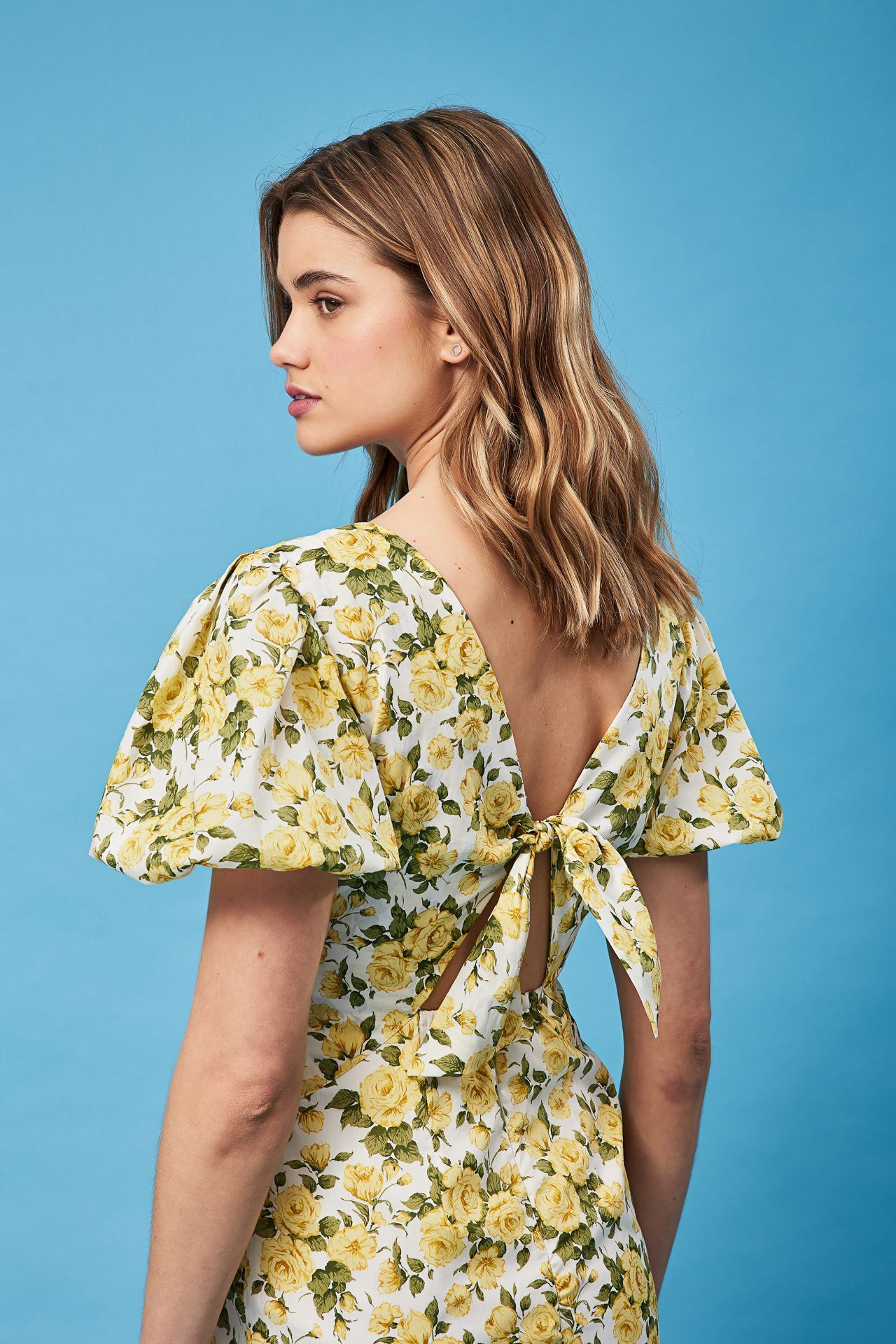 The back of a woman wearing a yellow and white floral dress.