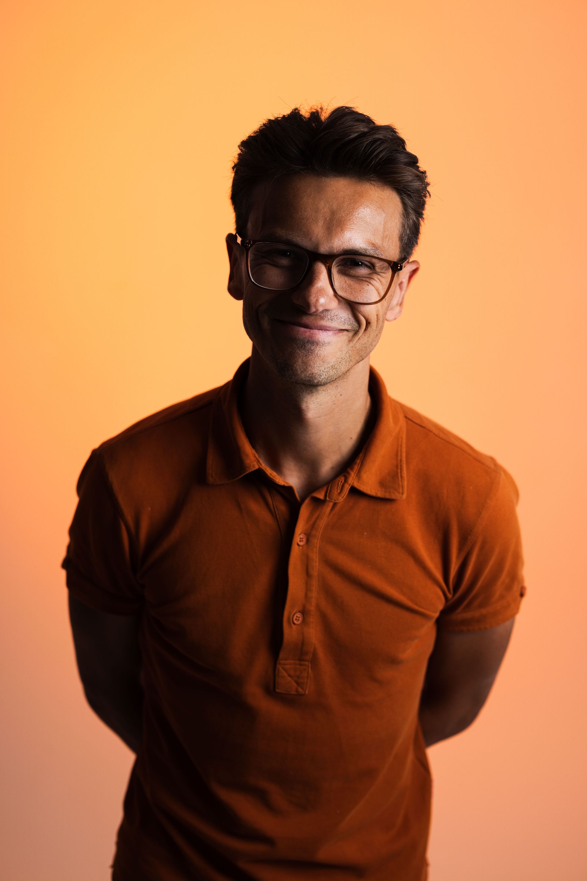 a man wearing glasses and a light blue shirt is smiling for the camera .
